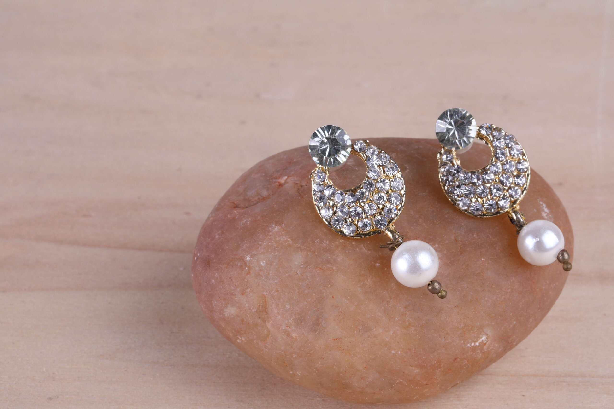 Sparkling diamond and pearl earrings elegantly displayed on a stone for a stylish look.